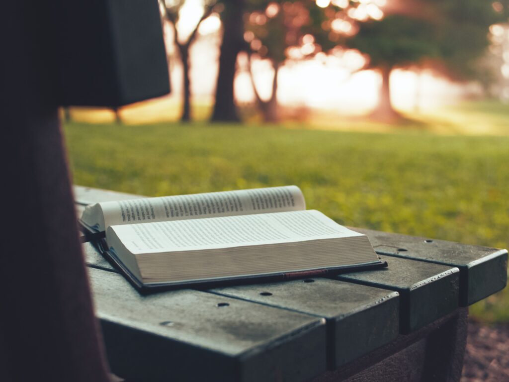 An open book sitting on a park bench