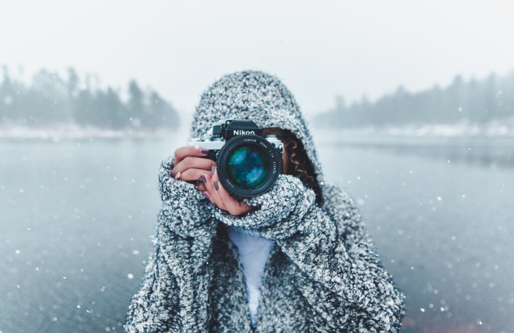 A person standing in a snowy landscape with a camera